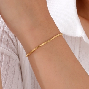 Minimalist gold snake bone chain bracelet worn on wrist with elegant knit fabric