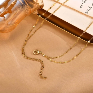 Collier doré élégant avec perles délicates sur un fond de tissu texturé chic