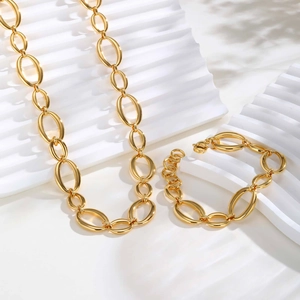 Golden stainless steel chunky oval link necklace and bracelet set on a white platform