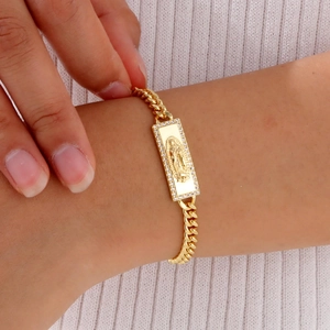 Detailed macro view of gold-plated Virgin Mary pendant on Cuban chain bracelet
