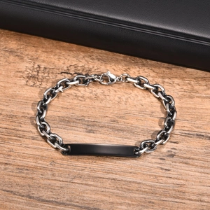 Détail d'un bracelet gourmette en acier avec plaque d'identité noire sur fond bois