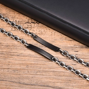 Détail d'un bracelet gourmette en acier avec une plaque d'identité noire polie
