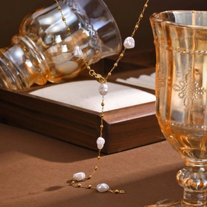 French style gold Y-necklace with baroque pearls on a warm wooden display stand