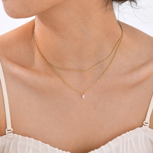 Double-layered gold stainless steel necklace with white zircon pendant on model