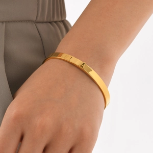 Bracelet jonc ouvert en acier inoxydable doré poli avec détail lettre A porté au poignet