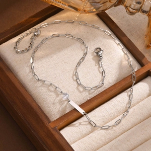 Detail of silver paperclip chain necklace with round zircon and rectangle metal plate