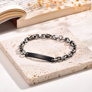 Détail d'un bracelet en acier inoxydable avec plaque noire sur une plaque de pierre