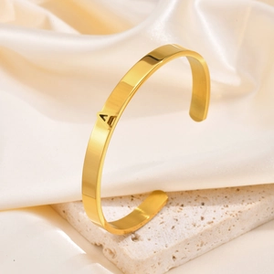 Bracelet jonc ouvert en acier doré poli avec lettre A en relief sur une base luxueuse