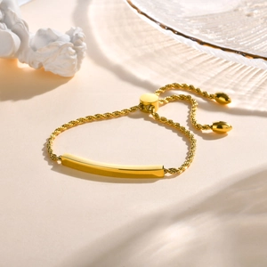 Détail macro du bracelet gourmette torsadé doré avec barre incurvée et polie
