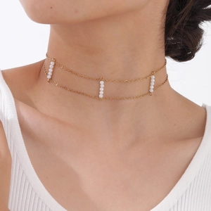 Detail of double-layered gold choker with white crystal beads on a model's neck