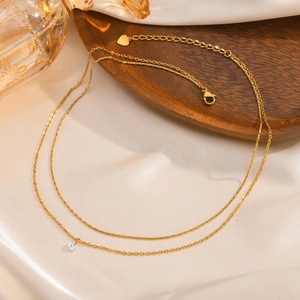 Double-layered gold stainless steel necklace with white zircon pendant on silk fabric