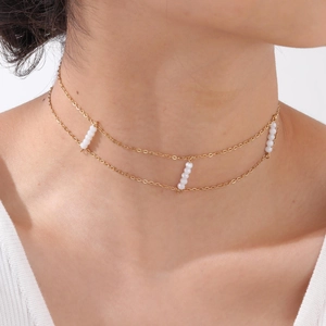 Detail of double-layer golden cross chain necklace with white crystal faceted beads on neck