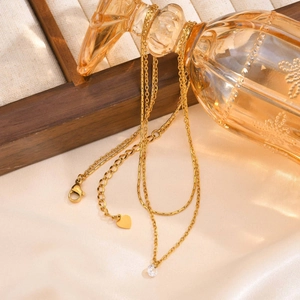Double layered gold stainless steel necklace with white zircon and heart charm on glass bottle