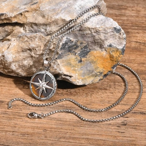 Detailed close-up of octagram compass necklace with brown tiger eye stone on natural rock
