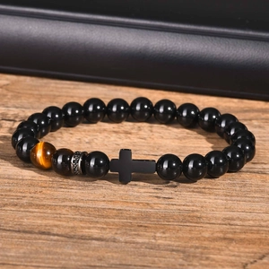 Men's beaded bracelet with black onyx, tiger eye stone and matte cross on wood surface
