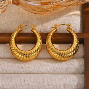 Detail of golden C-shaped hoop earrings with croissant textured pattern in a jewelry box