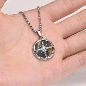 Men's necklace detail with tiger eye stone pendant and octagram star held in hand