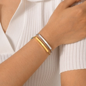 Détail de bracelets barre dorés et argentés au poignet avec finition polie élégante