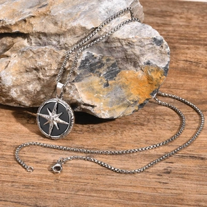 Detail of silver square pearl chain with compass star pendant on natural stone base