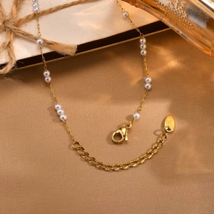Detailed macro view of the gold lobster clasp and K18 engraved tag on the pearl necklace