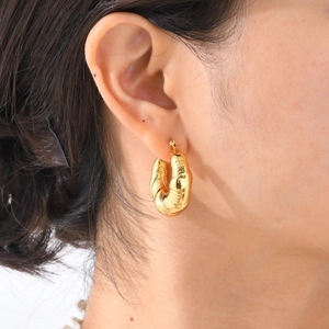 Polished gold croissant hoop earrings with textured ribbed design worn by a woman