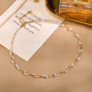 Détail d'un collier doré double rangée avec petites perles, fermoir homard et tag K18