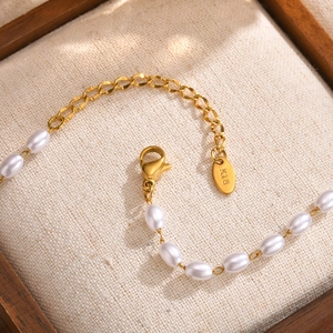 Detail of K18 engraved tag and lobster clasp on pearl chain gold necklace