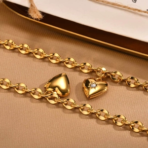 Dettaglio macro di braccialetti con medaglione a cuore in acciaio dorato e zircone
