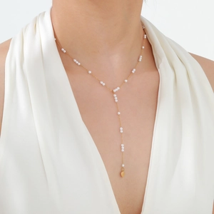 Detail of elegant gold Y-shaped necklace with white pearls and small heart pendant