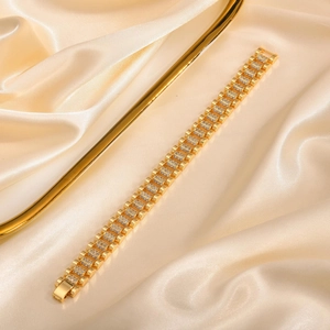 Close-up of gold link bracelet with white zircon inlay on golden silk fabric