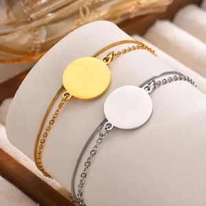 Double-layered gold and silver stainless steel chain bracelet with a round tag charm