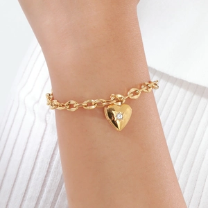 Dettaglio di un bracciale a cuore in acciaio dorato con zircone indossato sul polso