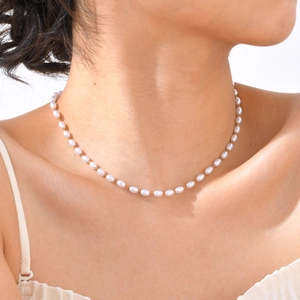 Detail of elegant gold chain necklace featuring high-quality white oval pearls for women