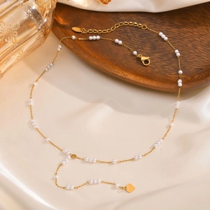 Elegant gold Y-shaped necklace with white pearls and heart charm on silk background
