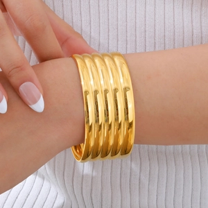 Detail shot of chunky gold bangle set with grooved design and high polish finish