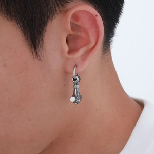 Gros plan d'une boucle d'oreille marteau de Thor en acier inoxydable porté à l'oreille