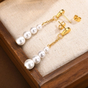Boucles d'oreilles pendantes dorées avec quatre perles blanches graduées sur boîte