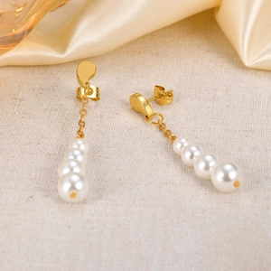 Vue détaillée des boucles d'oreilles dorées en virgule avec dégradé de quatre perles