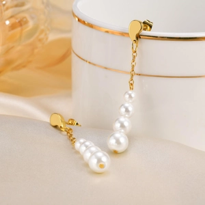 Gros plan de boucles d'oreilles pampilles dorées avec perles sur tissu de soie doux