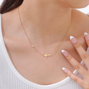 Nahaufnahme einer goldenen Edelstahl-Kreuzkette mit Zirkonia-Stein auf einem Frauenhals