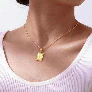 Close-up of golden tulip rectangular pendant necklace worn on a collarbone