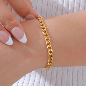 Primo piano di un bracciale a catena cubana dorata lucida indossato su un maglione