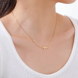 Nahaufnahme einer minimalistischen Goldkreuz-Halskette mit Zirkonia am Modell