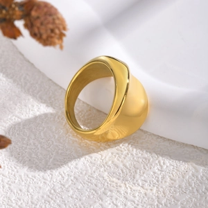 Bague dôme dorée minimaliste avec surface polie miroir sur fond texturé blanc