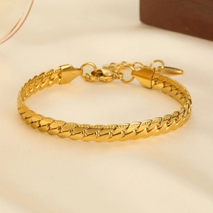 Dettaglio ravvicinato del bracciale a catena dorata con incisioni su raso liscio