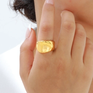 Gros plan détaillé d'une bague large irrégulière en acier inoxydable doré au doigt