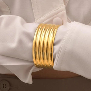 Polished chunky gold cuff bracelet with 5-layer textured ribbing over shirt sleeve