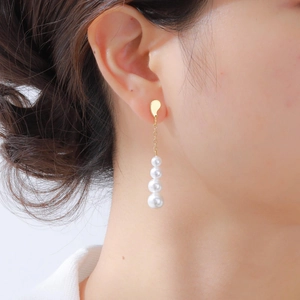 Élégantes boucles d'oreilles dorées avec perles blanches dégradées portées par un mannequin