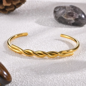 Macro shot of gold twisted cable cuff bracelet with polished surface on white stones