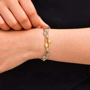 Vue macro d'un bracelet bicolore avec maillons épingles de sûreté et breloques cœurs